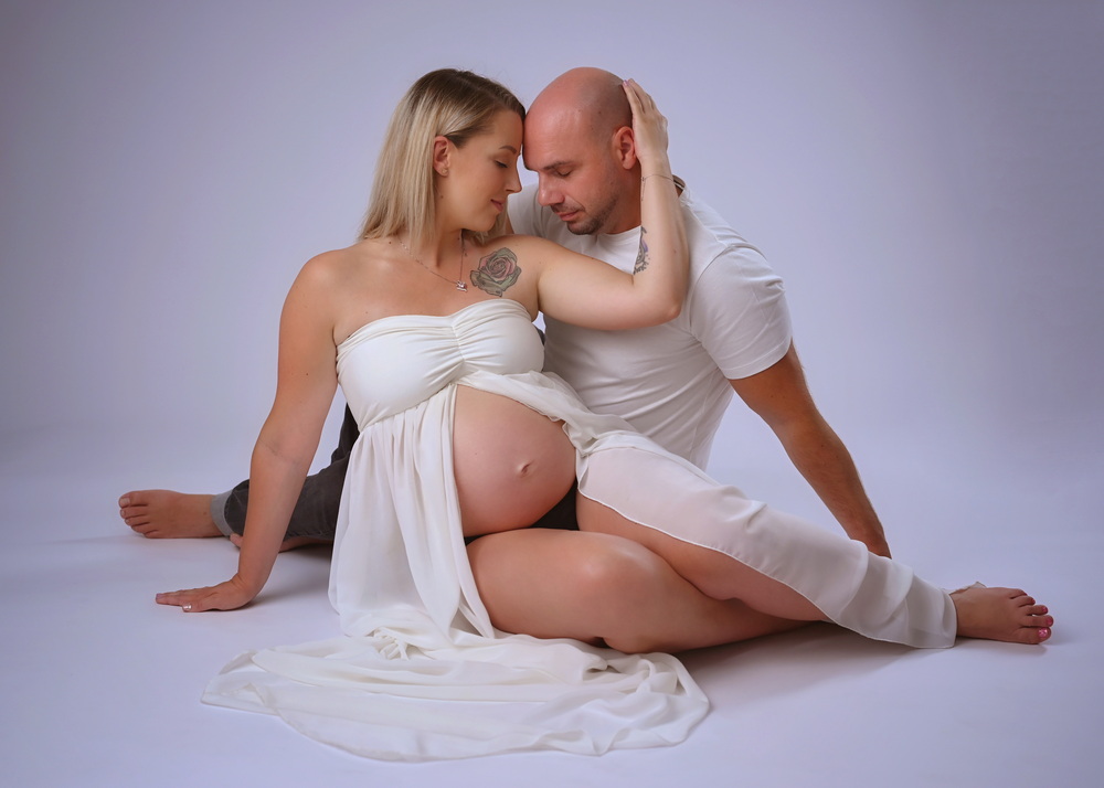 Wunderschöne Babybauch Fotografie im Studio und outdoor Eine werdende Mutter liebevoll dargestellt mit Ihrem Babybauch im warmen Studiolicht
