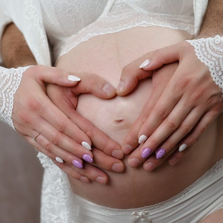 Wunderschöne Babybauch Fotografie im Studio und outdoor Eine werdende Mutter liebevoll dargestellt mit Ihrem Babybauch im warmen Studiolicht