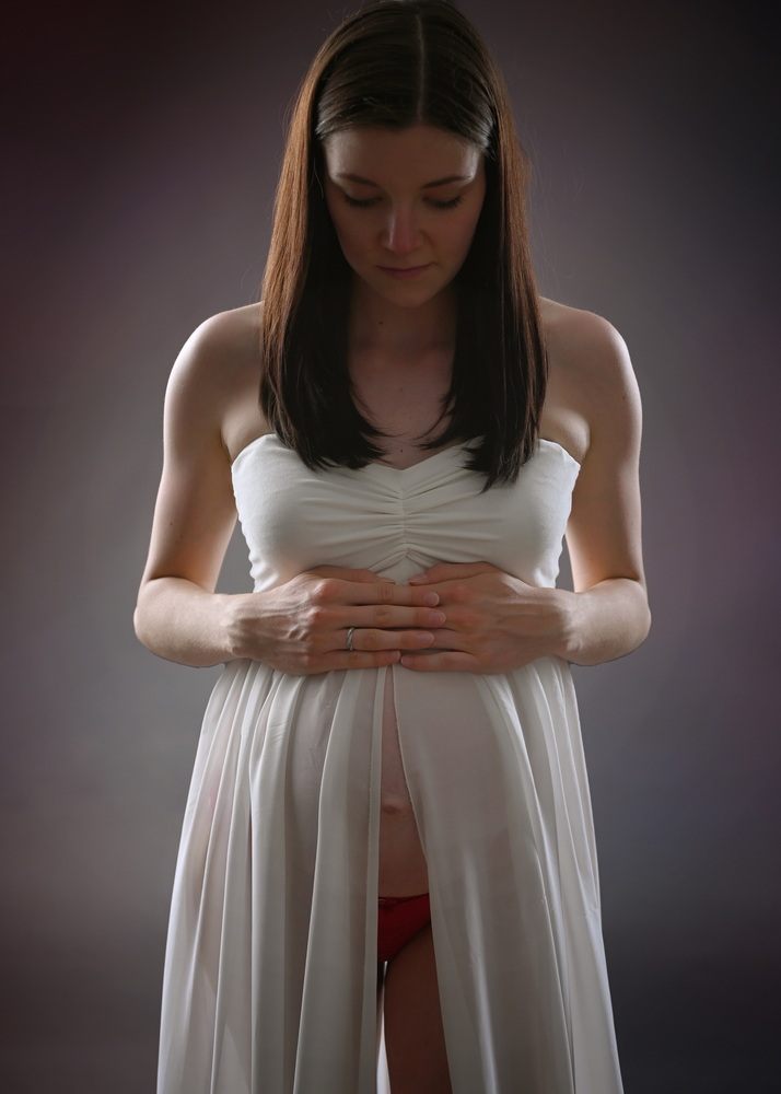 Wunderschöne Babybauch Fotografie im Studio und outdoor Eine werdende Mutter liebevoll dargestellt mit Ihrem Babybauch im warmen Studiolicht