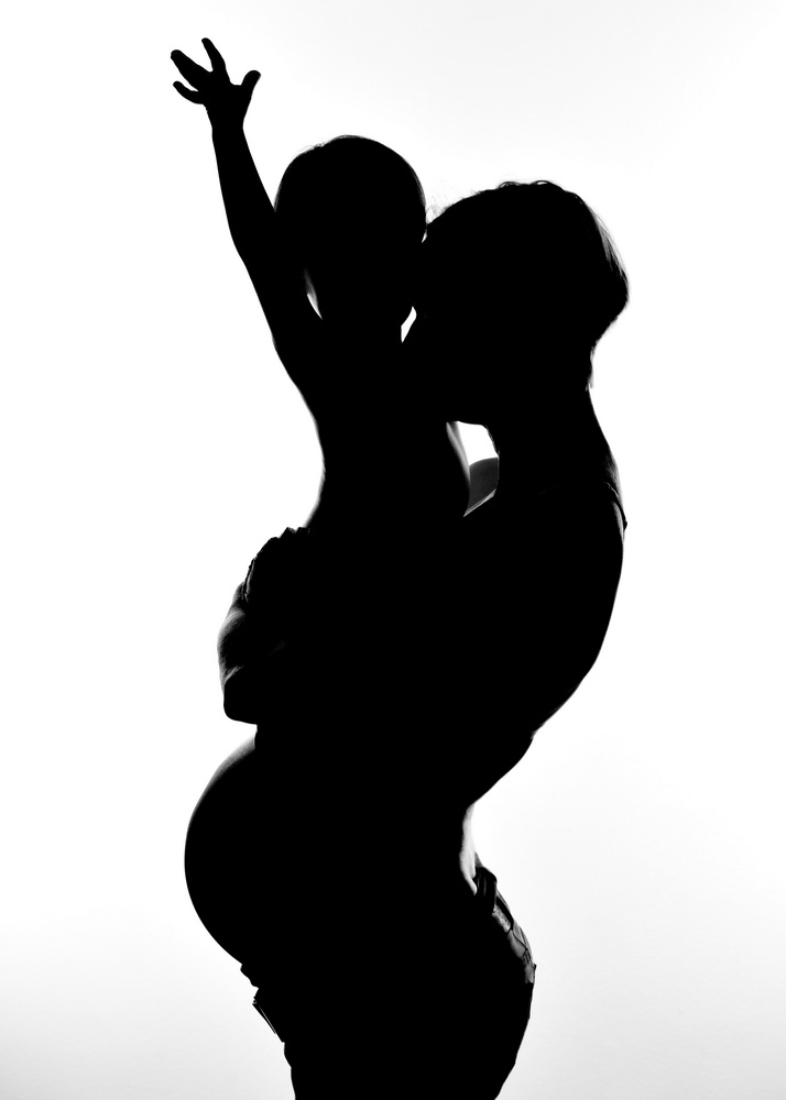Wunderschöne Babybauch Fotografie im Studio und outdoor Eine werdende Mutter liebevoll dargestellt mit Ihrem Babybauch im warmen Studiolicht